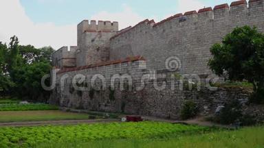 君士坦丁堡的西奥多西亚城墙，有绿色的庄稼，红色的板条箱和一个塔楼。